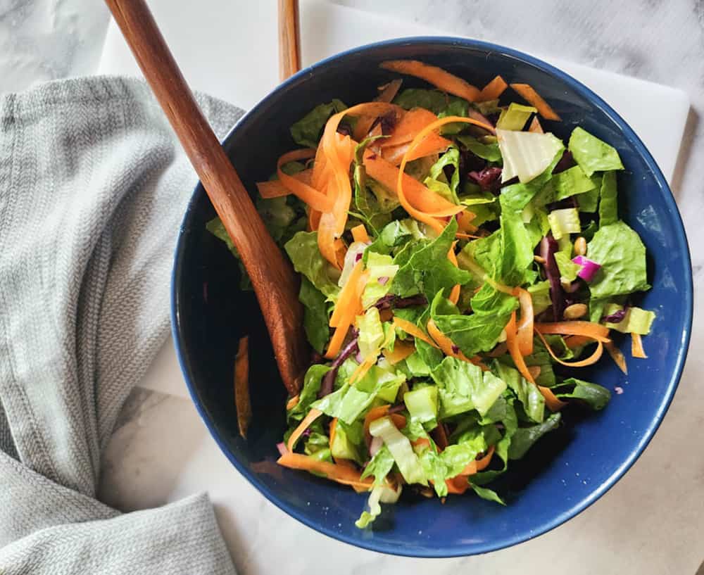 an overhead view of last step, tossed salad in a bowl