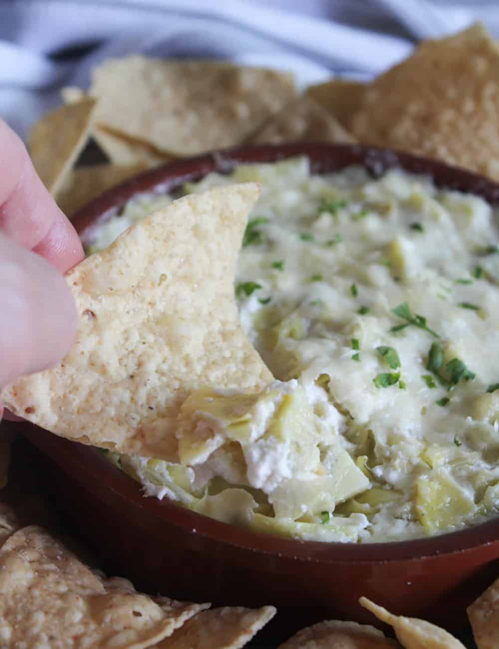 a picture of a chip dipping into the artichoke dip