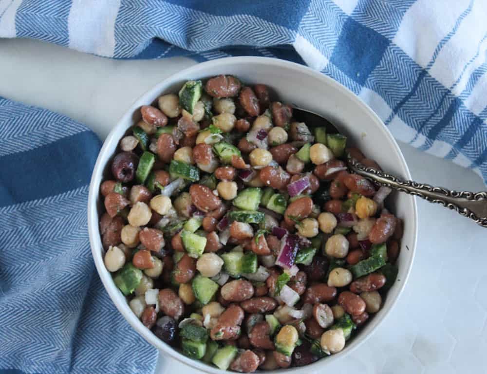 an overhead view of bean salad in a bow with a spoon