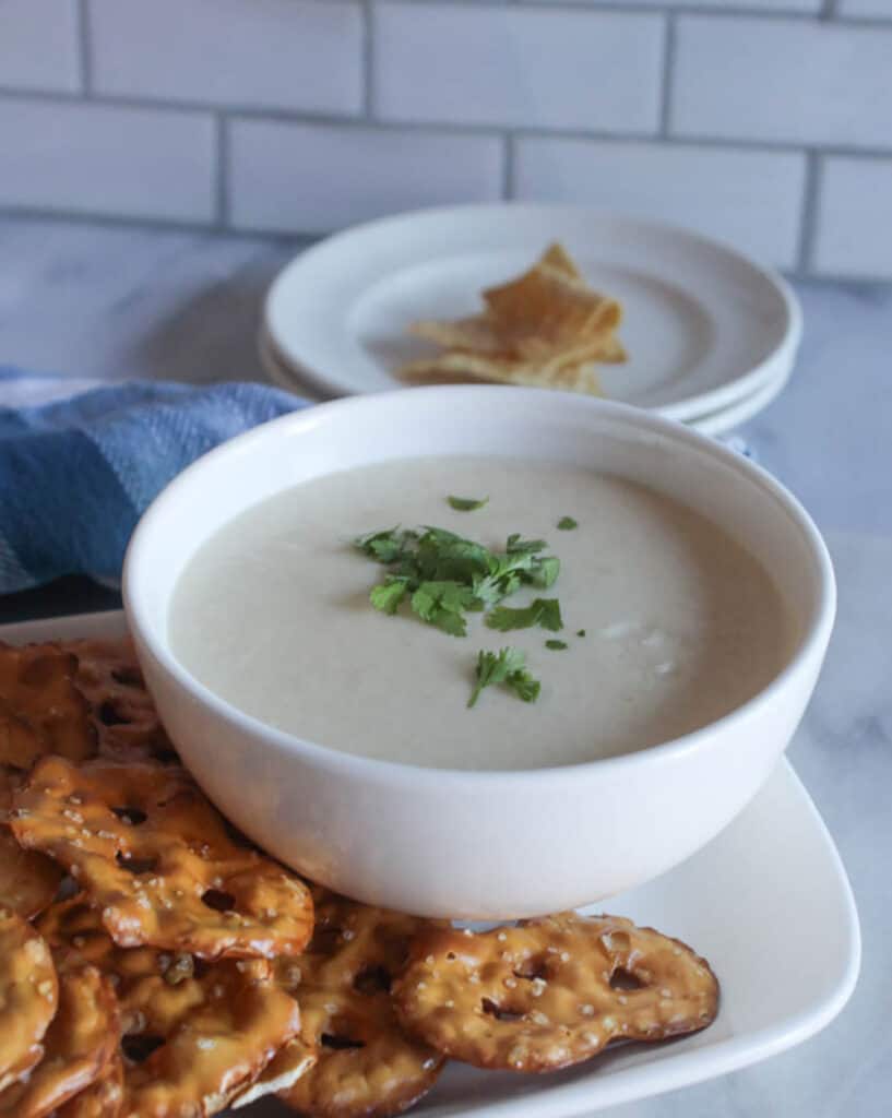 a close up picture of beer cheese dip with pretzels on a plate