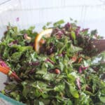 A close up picture of kale salad in a glass bowl