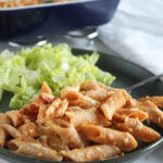 a close up picture of buffalo chicken pasta on grey plate with a salad