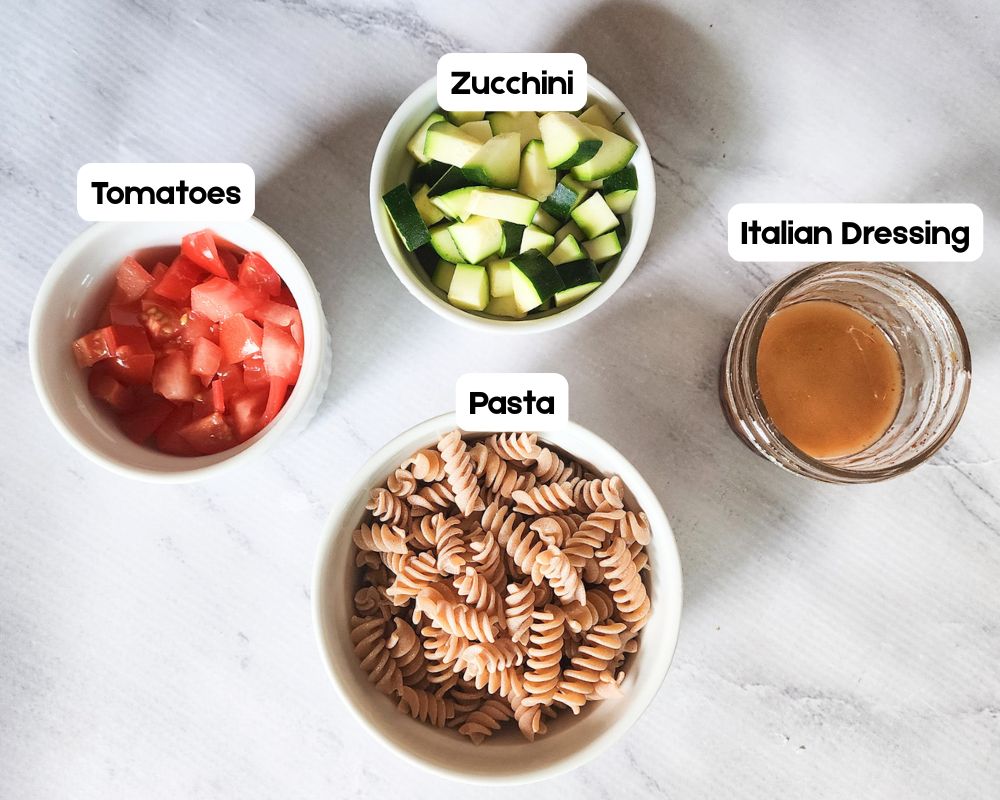 a picture of 4 ingredients needed for pasta salad: pasta, tomatoes, zucchini and italian dressing in separatte white bolws