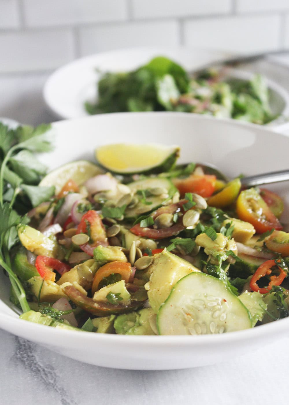 avocado salad in a bowl with lime wedges fro garnish
