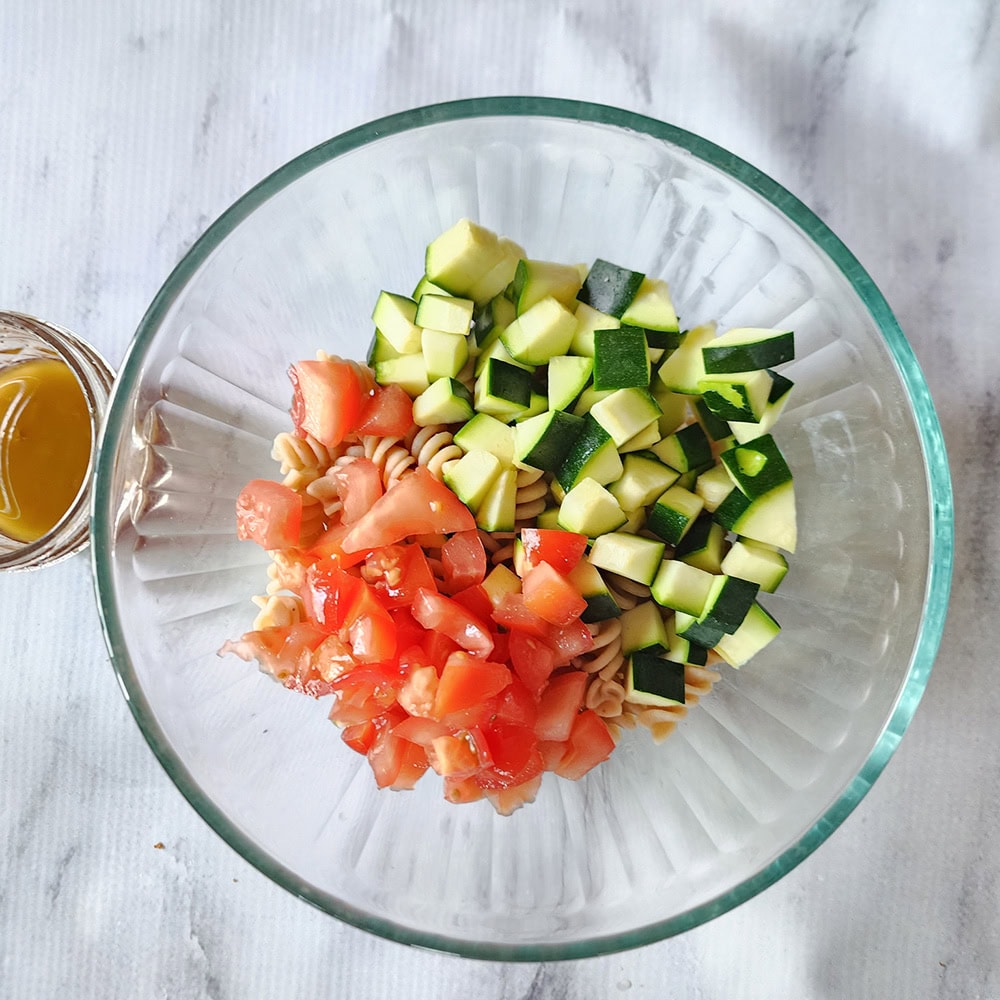 a picture of the ingrdiuents for the pasta salad in a bowl not mixed