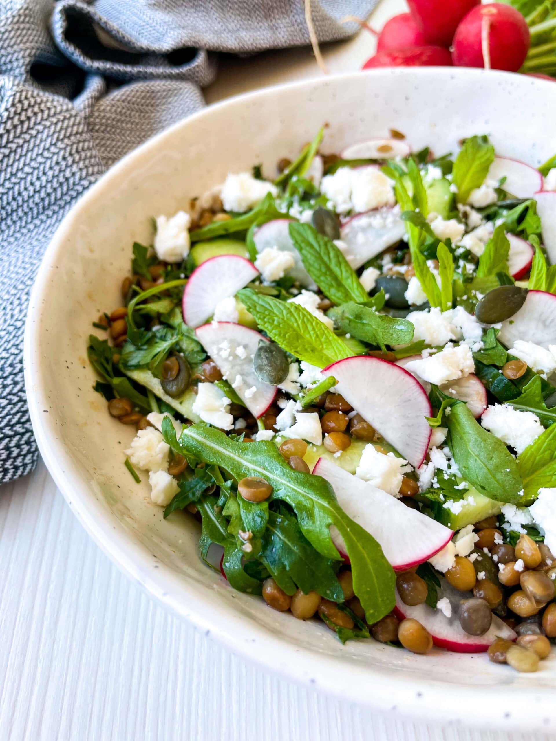Lentil salad in a bowl with radishes, feta cheese and baby arugula