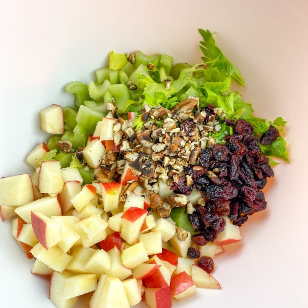 process step 2 for apple celery salad, the ingredients in a bowl not mixed