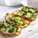 4 cheesy broccoli filled air fryer potato skins on a white plate
